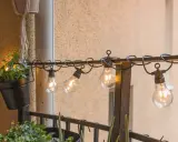 Mysig balkong inspiration med slingor av glödlampor och gröna växter. Perfekt för sommarkvällar.