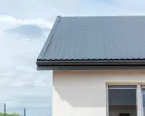 Nowy dach z szarej blachy, gotowy na deszcz. Układanie blachy na dachu zakończone.