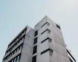 Betonowy budynek o geometrycznej bryle, z rzędami okien. Ta kategoria obiektu budowlanego dominuje w kadrze.