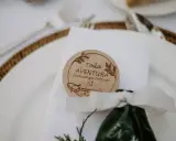 Detalle de mesa de boda con un distintivo de madera que dice "Toda aventura comienza con un SÍ". Ideas para nombres de mesas de boda.
