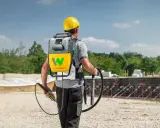 Bauarbeiter mit Rucksackeinheit und Rüttler zur Beton verdichten auf einer Baustelle.