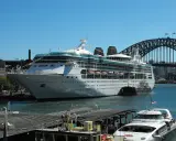 La Rhapsody of the Seas, un'imponente nave da crociera, attracca nel porto di Sydney, con l'iconico ponte sullo sfondo.