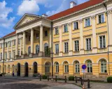 Imponujący żółty budynek z kolumnami, jeden z wielu **uczelni publicznych w Warszawie**.