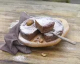 Gâteau au chocolat saupoudré de sucre glace, avec des châtaignes. Une part est coupée, prête à être dégustée. Une recette de châtaigne à essayer !