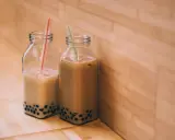 Två flaskor med boba, en populär dryck i Stockholm, står på ett träbord.