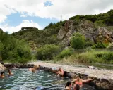 Gente disfrutando de las piscinas naturales en La Rioja, rodeadas de vegetación y rocas.