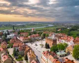 Urokliwy rynek i rzeka w miasto zakochanych w Polsce. Dachy kamienic i zieleń tworzą malowniczy krajobraz.