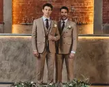 Two men in tan suits stand side-by-side. The man on the left wears a single-breasted suit, while the man on the right wears a double-breasted suit.