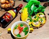 Bouteille de sauce poisson asiatique Phu Quoc, plat de crêpes garnies de calamars et de légumes, et un bol de boulettes.