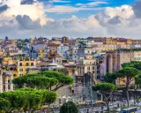 Vista panorámica de Roma con edificios históricos y pinos. Jóvenes exploran la ciudad eterna, disfrutando de su belleza.