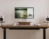 Minimalistyczny blat zamiast biurka inspiracje: monitor, białe głośniki, drewniana szuflada, klawiatura i myszka.