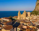 Cefalù cosa vedere: la maestosa Cattedrale Normanna domina il borgo con le sue torri, incastonata tra il mare blu e la rocca imponente.