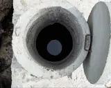 Otwarty betonowy właz szamba, widok z góry. Rozważasz, jak uszczelnić szambo betonowe od środka?