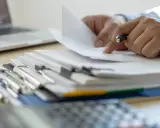 Ręce przeglądają dokumenty, szukając informacji, kiedy można wymeldować członka rodziny.