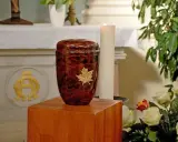 Elegancka, brązowa urna z liściem klonu, symbolizująca pamięć. To miejsce spoczynku prochów, co to urna.