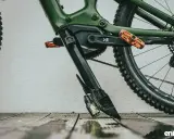 Zielony rower elektryczny z pomarańczowymi pedałami. Widoczny mechanizm, który ułatwia zrozumienie, jak wyjąć baterię z roweru elektrycznego.