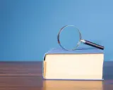 Lente d'ingrandimento su un libro blu, per capire il hic et nunc significato.