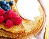 En hög med nyttiga pannkakor toppas med grädde, hallon och blåbär. En perfekt frukost eller mellanmål.