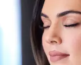Una mano sostiene un spray fijador de maquillaje rojo. Ideal para cuando usar y mantener tu look perfecto.
