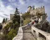 Sentiero roccioso verso le torri di San Marino, un viaggio nella storia. Turisti salgono la scalinata che porta alle antiche fortificazioni.