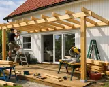 Man bygger en pergola på altanen. Trämaterial, såg och verktyg ligger redo.