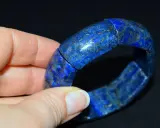 Błękitna bransoleta z lapis lazuli, z widocznymi złotymi inkluzjami pirytu, prezentowana na dłoni.