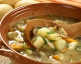 Zupa ziemniaczana przepis babci. Aromatyczna, sycąca zupa z ziemniaków, marchewki i grzybów, podana w glinianej misce z drewnianą łyżką.