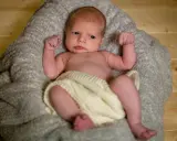 Un neonato con un'espressione curiosa, avvolto in una coperta, pronto per un servizio fotografico flash neonati.