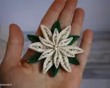 Un fiore di carta in quilling, perfetto per un tutorial di quilling natale. Dettagli dorati e petali bianchi e verdi.