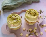 Dwa pucharki z kremem pistacjowym z mascarpone, udekorowane posiekanymi pistacjami.