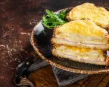Deux croque monsieur bechamel dorés, garnis de jambon et de fromage fondant, servis avec une salade verte.