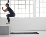 Frau macht **box jumps** in einem hellen Raum mit großen Fenstern.
