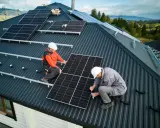 Zwei Monteure installieren Solarmodule auf einem Dach. Die Frage "was kostet eine PV Anlage mit Speicher" beschäftigt viele Hausbesitzer.