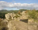 Paisaje rocoso con vegetación y colinas boscosas al fondo. Un lugar ideal que ver en Prades para disfrutar de la naturaleza.