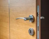 Porte isolante thermique entre garage et maison, en bois clair avec poignée chromée.