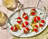 Szybkie przekąski na ognisko: pomidorki koktajlowe z mozzarellą i bazylią na patyczkach, polane sosem.