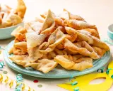 Un piatto colmo di chiacchiere, dolci tipici di Carnevale, cosparse di zucchero a velo. Festa e gusto, ecco cosa si mangia a Carnevale!