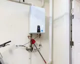 Moderner durchlauferhitzer mit digitaler Anzeige (120F) neben einem Fahrradlenker und einer weißen Tür.