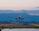 Ett flygplan landar vid Korfu flygplats i skymningen. Landningsbanans ljus lyser upp vägen.
