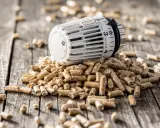 Ein Thermostat auf einem Haufen Holzpellets. Die Frage "wie lange heizt man mit 1 tonne pellets" wird hier visuell thematisiert.