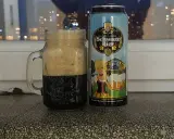 Perlenbacher Schwarz Bier w kuflu, obok puszka piwa. Wieczorny widok na miasto w tle.