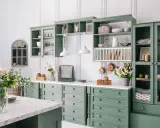 Cucina in stile provenzale casa con mobili verdi, pentole in rame appese e fiori freschi.