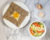Une délicieuse crêpe complète bretonne avec un œuf coulant, accompagnée d'une salade fraîche.