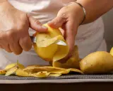 Hände schälen Kartoffeln für die Zubereitung. Bald sind die Kartoffeln gar und bereit zum Genuss.