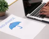 Koniec leasingu a ubezpieczenie: dokument z parasolką i dłonie piszące na laptopie.