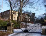 Här bor prins Carl Philip. Villa Solbacken, en vacker byggnad med en imponerande grind, omgiven av träd och snö.