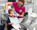 Dziecko w masce do sedacji wziewnej. Dentystka monitoruje stan pacjenta, minimalizując potencjalne skutki uboczne.