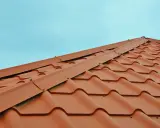 Nowe, brązowe dachówki tworzą piękny wzór. Zastanawiasz się, jak obliczyć kąt nachylenia dachu? Ten widok może pomóc.