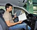 Mężczyzna w kabinie Renault Megane 3 porównuje stary i nowy filtr kabinowy, przygotowując się do jego wymiany.