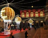 Luci scintillanti e palloni luminosi creano un'atmosfera magica per un week end a Rimini. Persone passeggiano su un tappeto rosso, ammirando le decorazioni natalizie.